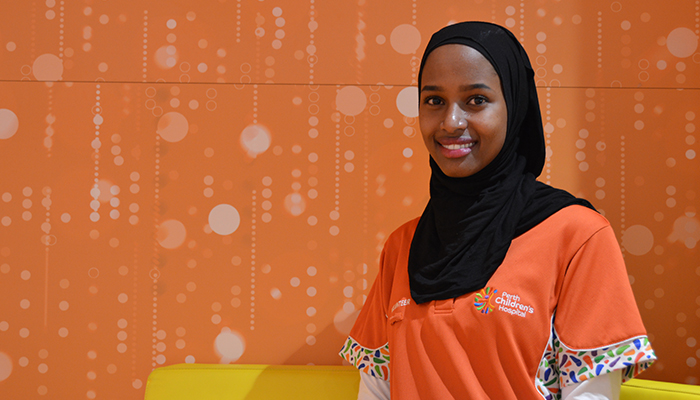 Woman in headscarf sitting again orange background