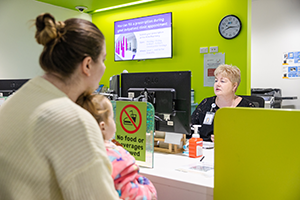 Mum and child at the admissions desk being served by a clerk
