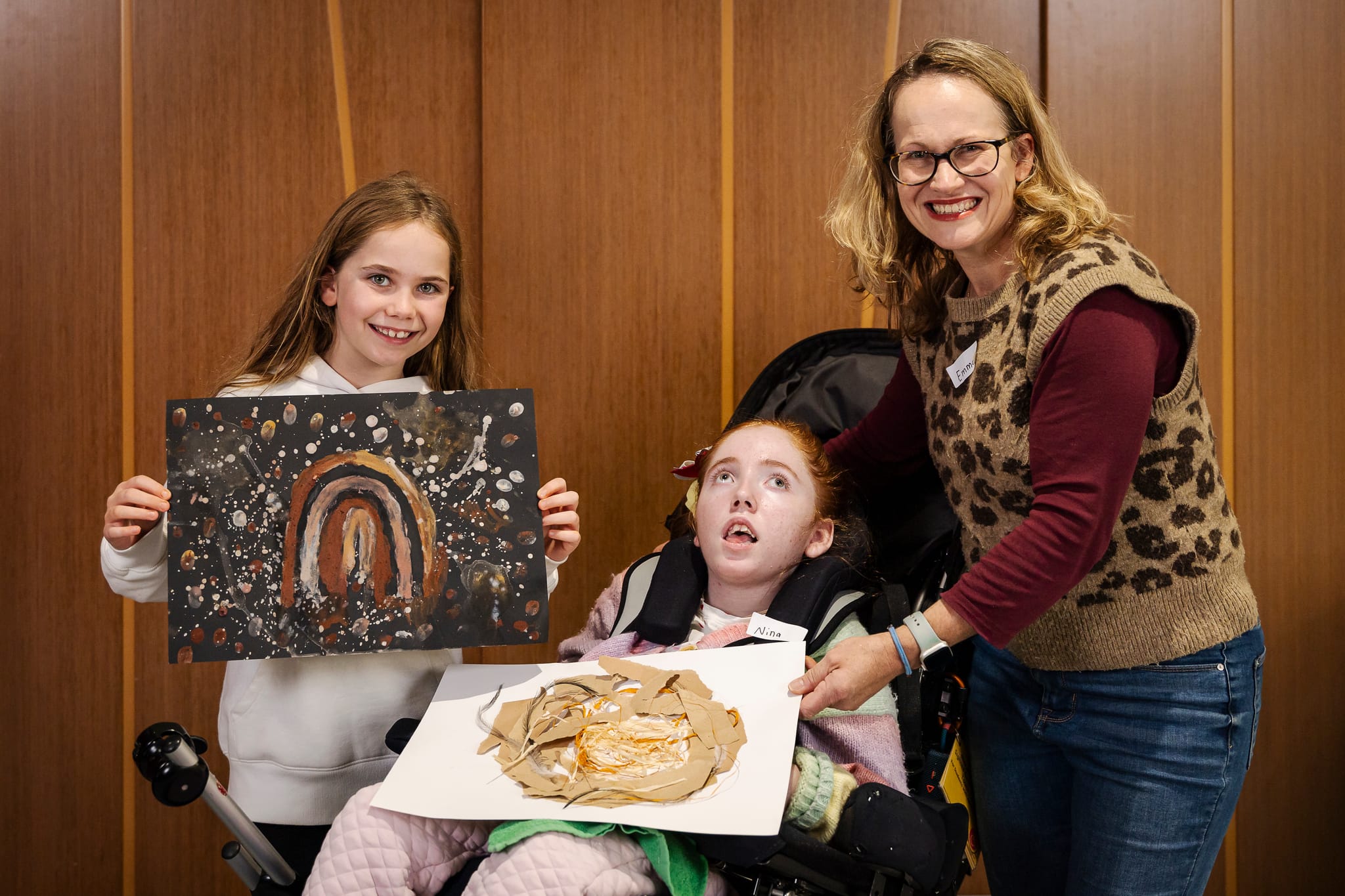 A family holding up their artwork created during the workshop.