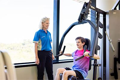 Boy sitting on exercise machine, doing arm exercises